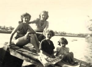 Quatre femmes souriantes sur un pont au bord de l'eau.
