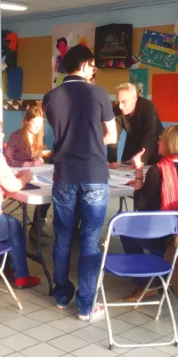 Groupe de personnes participant à une réunion ou un atelier dans une salle communautaire.