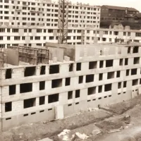 Bâtiment en construction avec échafaudages, vue aérienne, style architectural typique des années 80.