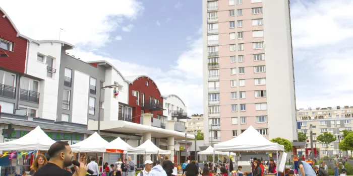 Marché animé en plein air avec un immeuble de grande hauteur en arrière-plan.