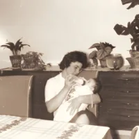 Mère et bébé se câlinent tendrement dans un intérieur chaleureux et nostalgique.