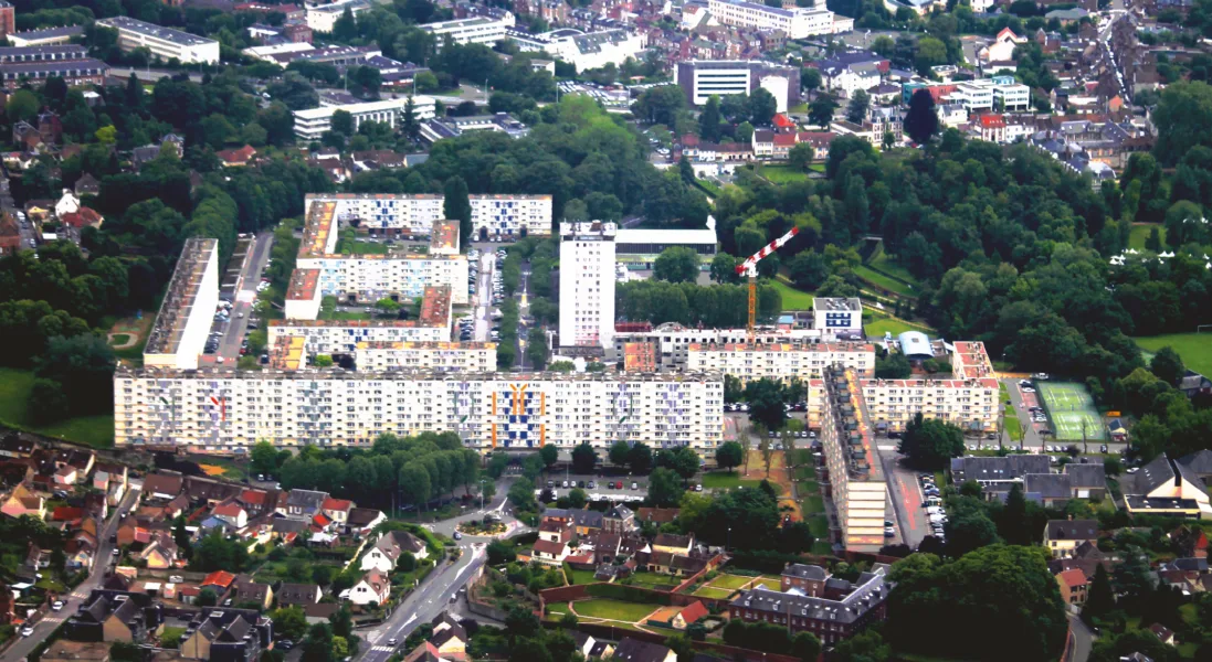 Vue aérienne d'un ensemble de logements sociaux à Luxembourg, entouré de verdure.