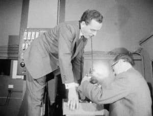 Deux hommes travaillent sur un ordinateur ancien dans un laboratoire.