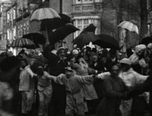 Une foule sous des parapluies dans une rue pluvieuse, ambiance parisienne du début du XXe siècle.