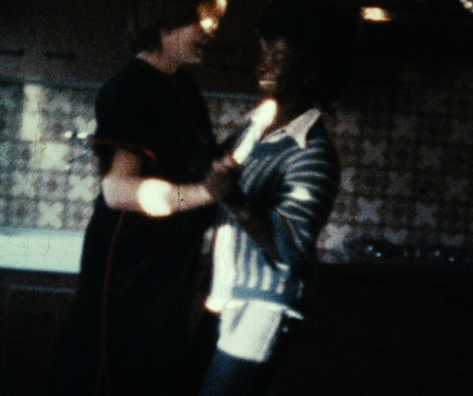 Deux personnes se serrent dans l'obscurité, partageant un moment intime et chaleureux.