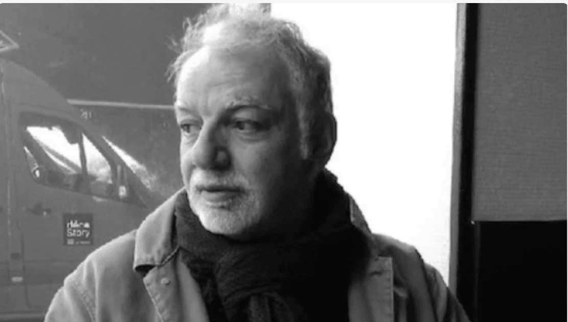 Portrait en noir et blanc d'un homme âgé, pensif, regardant par la fenêtre.