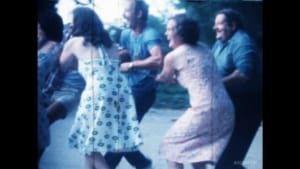 Des personnes dansent joyeusement dans un jardin, une scène nostalgique et colorée.