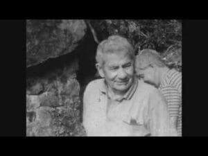 Un homme âgé sourit, entouré d'un jeune homme dans un environnement rocheux.