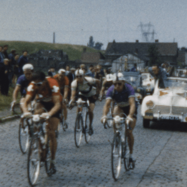 Cyclistes en compétition sur une route, suivis par une voiture de reconnaissance lors d'une course.