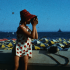 0590FH0009_jeune_fille_filme – Modifié Une jeune fille en maillot à pois prend une photo de la mer et des parasols.