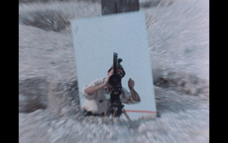 Un photographe prend une photo dans un environnement désertique et venteux avec son appareil.