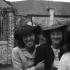 Deux jeunes femmes souriantes portant des chapeaux dans un décor rural.