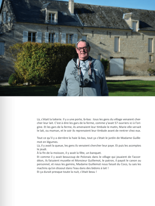 Un homme avec un appareil photo autour du cou pose devant une ancienne bâtisse en pierre.