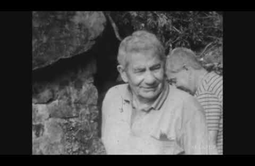 Un homme âgé sourit, entouré d'un jeune homme dans un environnement rocheux.